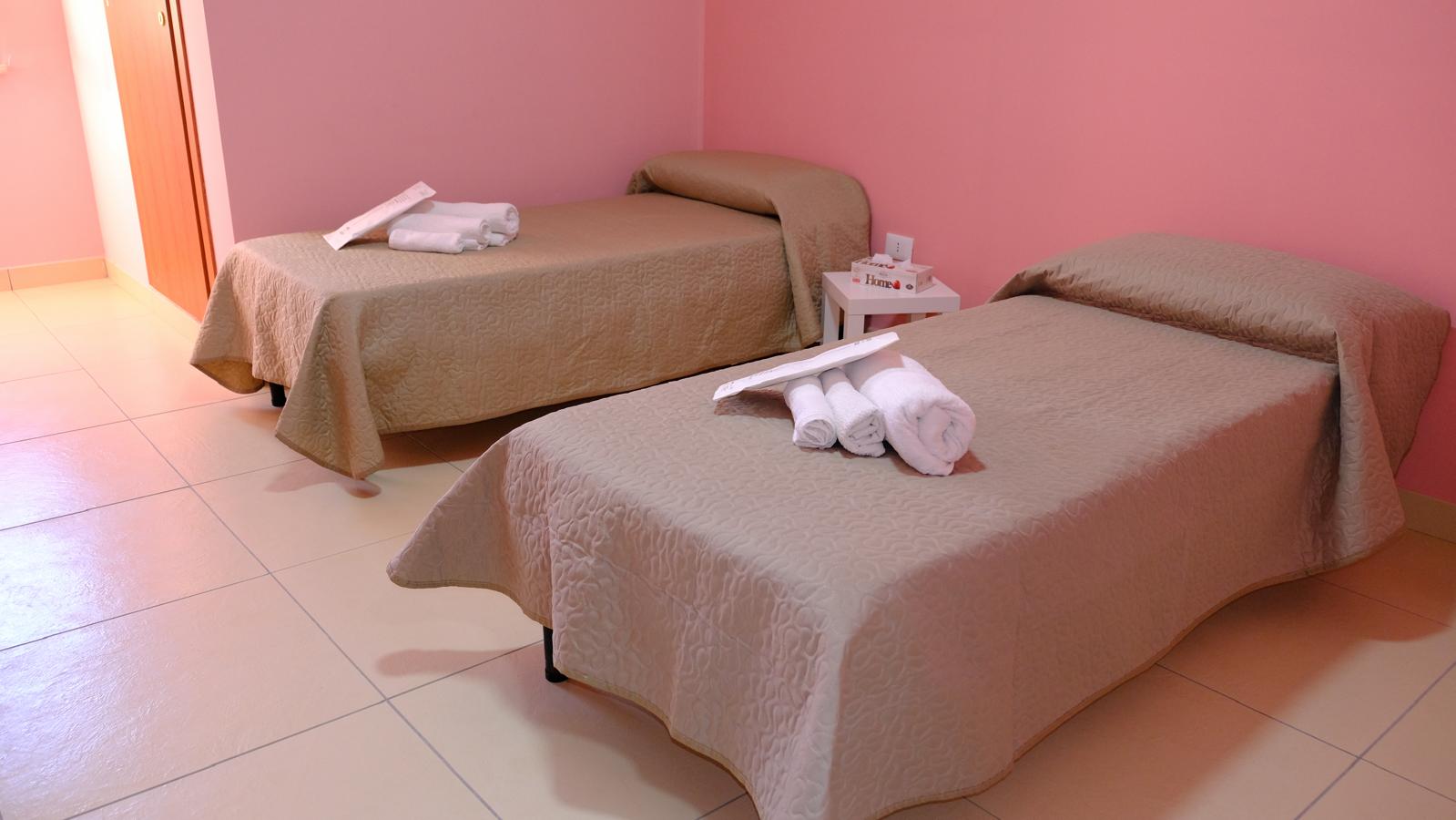Camera con due letti separati e pareti rosa negli alloggi Hermada